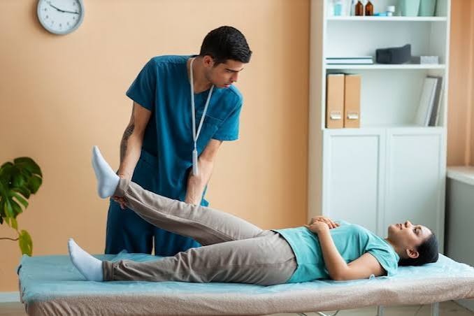 Physiotherapist guiding a patient through a supported leg raise on a treatment table