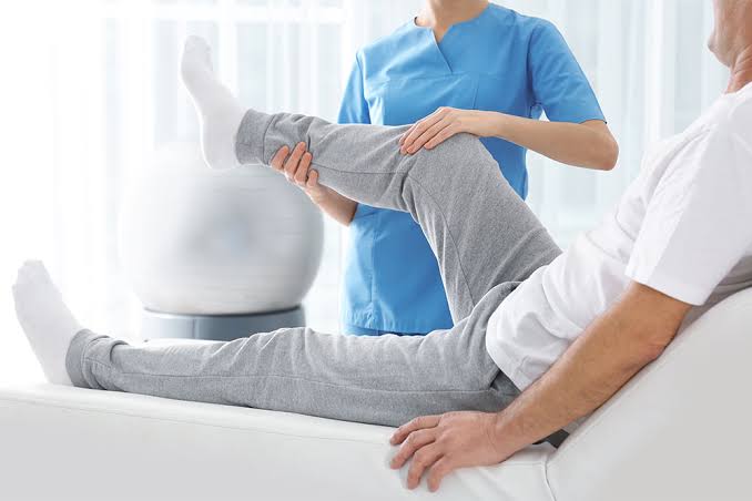 Physiotherapist supporting a patient's knee through a range of motion exercise